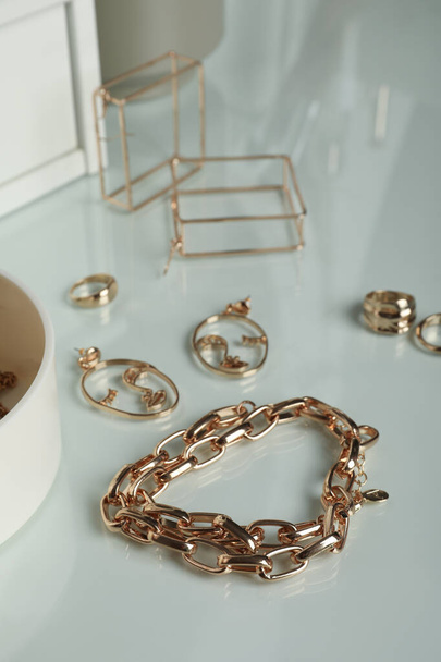 Stylish golden bijouterie on table, closeup. Elegant jewelry - Фото, зображення