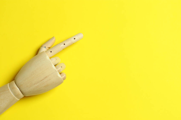 Wooden mannequin hand on yellow background, top view. Space for text - Фото, изображение