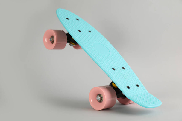 Turquoise skateboard on light grey background. Sport equipment - Фото, изображение