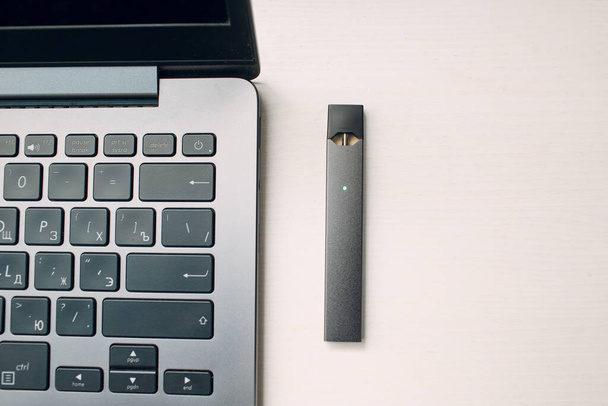 МОСКВА - 26 июня 2020 года: Juul электронная сигарета палочка никотинового пара и ноутбук - Фото, изображение