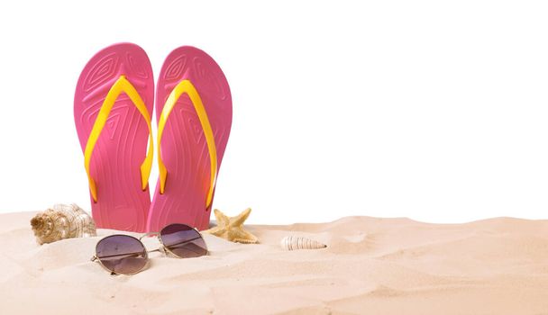 Pink flip flops, starfish, sea shell and sunglasses on sand against white background - Foto, immagini