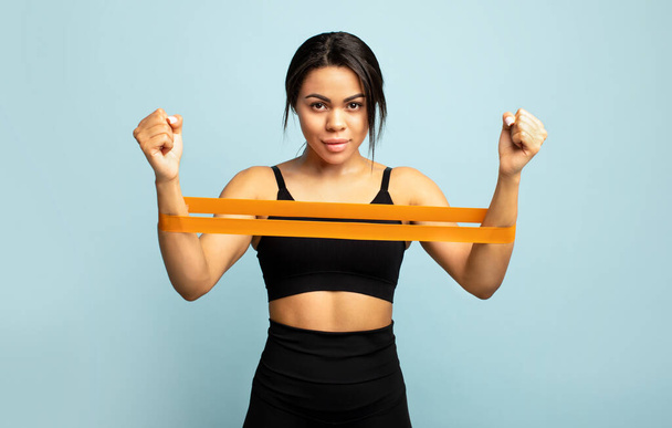 Síla a motivace. Africká americká sportovkyně cvičí pro ruce, cvičí s odbojovým pásmem - Fotografie, Obrázek