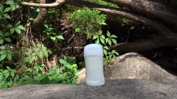 Plak deodorant verblijf op de steen in de buurt van groene boom met zonlicht en schaduwen - Video
