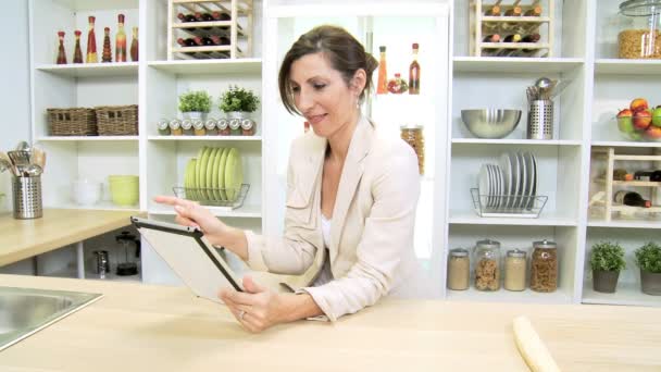 Empresaria inteligente en el mostrador de cocina usando tecnología inalámbrica
 - Imágenes, Vídeo