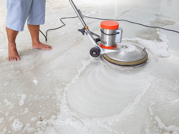 trabajador que utiliza la máquina de fregar para limpiar y pulir el piso en pies descalzos - Foto, Imagen