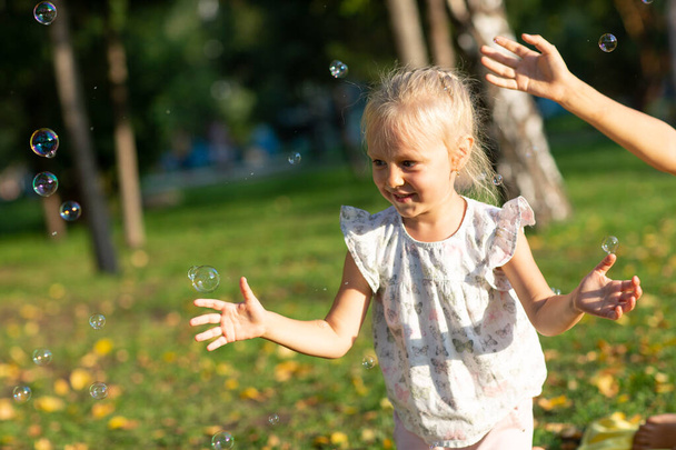 Cute little children boy and girl blowing bubbles in autumn park on sunny day - Photo, Image