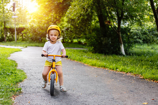 Little cute adorable caucasian toddler girl having fun riding exercise balance run bike push scooter in park forest.  - 写真・画像