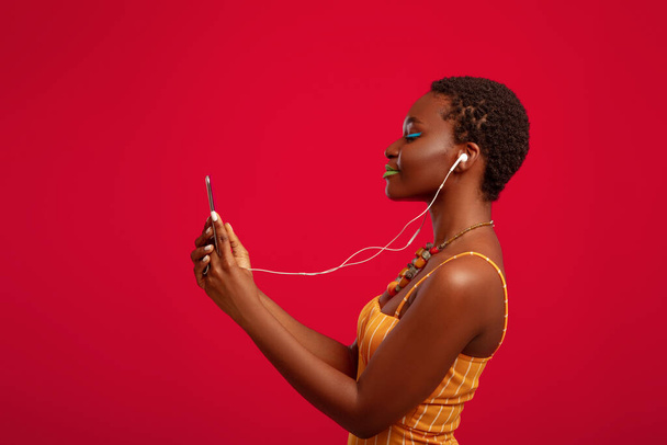Cute black woman listening to music on mobile phone - Foto, afbeelding