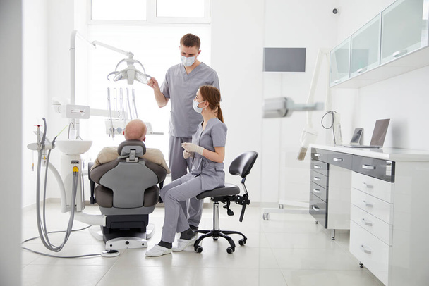 口腔外科手術のための歯の健康準備を分析し、病気の患者の口の中を見て、医療の制服を着た2人の医師。歯列矯正クリニックで働く病理医 - 写真・画像