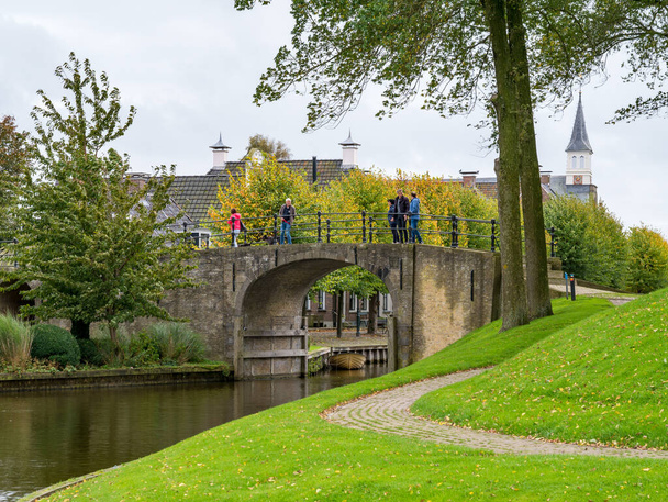 SLOTEN, NETHERLANDS - OCT 2, 2017: People walking on bridge of Woudsender water gate in fortified city of Sloten, Sleat, Friesland - 写真・画像