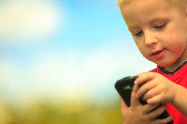 Little boy with mobile phone outdoor. - Fotó, kép