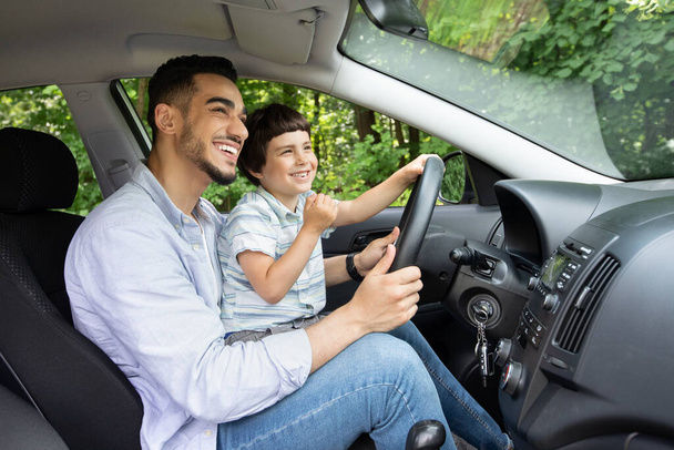 Młody arabski ojciec udziela lekcji jazdy swojemu małemu synowi - Zdjęcie, obraz