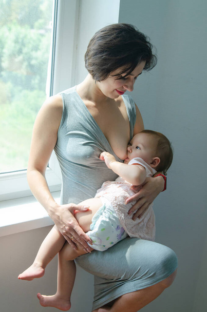 Een jonge blanke moeder geeft haar baby borstvoeding. In close-up genomen. Borstvoeding van zuigelingen. - Foto, afbeelding