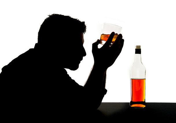 Silhouette de l'homme alcoolique ivre tenant bouteille de whisky contre le front se sentant déprimé souffrant de dépendance à l'alcool et problème d'alcoolisme isolé sur fond blanc
 - Photo, image