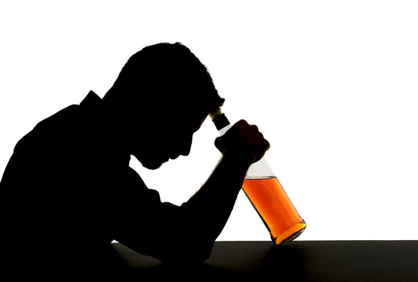 Silhueta de alcoólatra bêbado segurando garrafa de uísque contra a testa sentindo-se deprimido sofrendo de dependência de álcool e alcoolismo problema isolado em fundo branco
 - Foto, Imagem