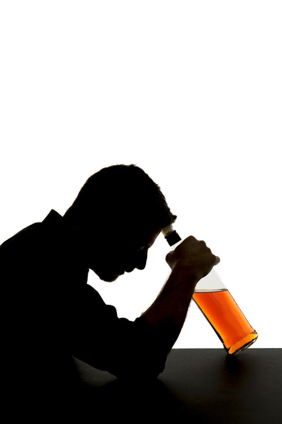 Silhouette of alcoholic drunk man holding whiskey bottle against forehead depressed suffering addiction problem - Photo, Image