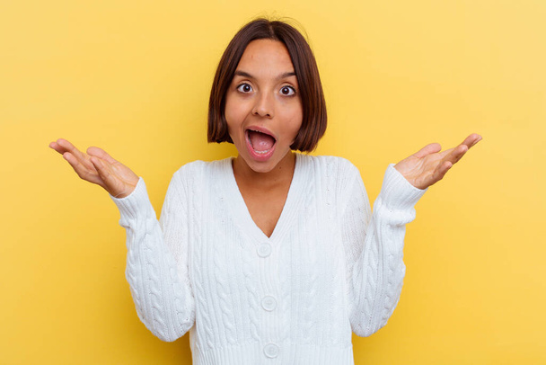 Young mixed race woman isolated on yellow background receiving a pleasant surprise, excited and raising hands. - Photo, Image