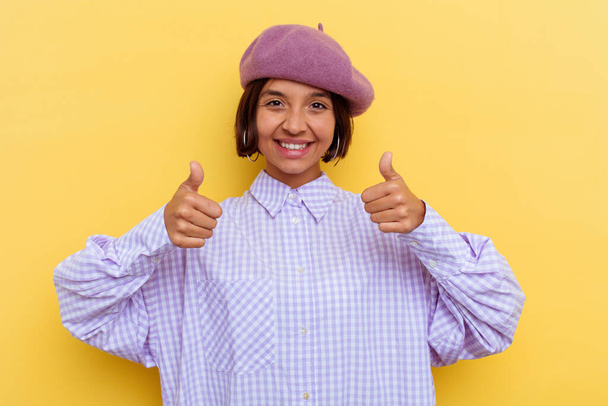 Giovane donna razza mista indossa un basco isolato su sfondo giallo con pollici in alto, applausi per qualcosa, sostegno e rispetto concetto. - Foto, immagini