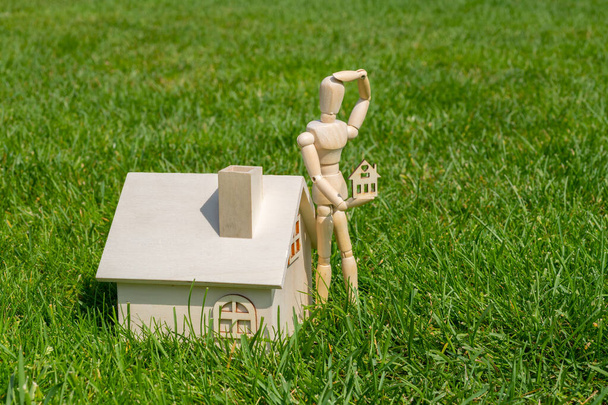 Figur einer hölzernen Person und symbolische Holzhäuser auf grünem Gras - Foto, Bild