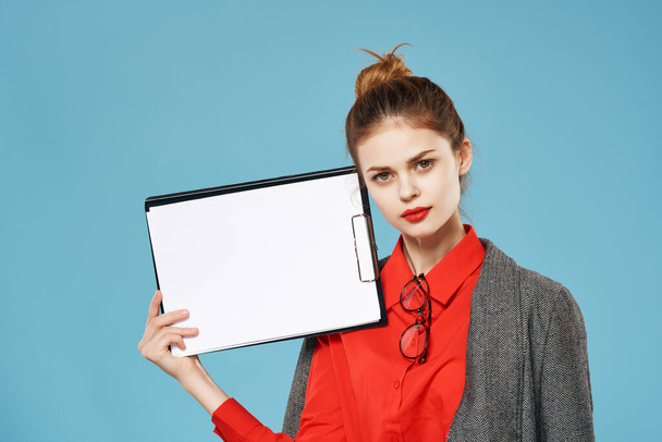 donna in camicia rossa con una giacca tiene un foglio di carta Copia Spazio sfondo blu - Foto, immagini
