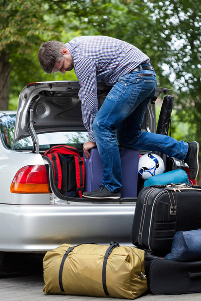 Man using his strength to packing luggage into car  - Фото, зображення