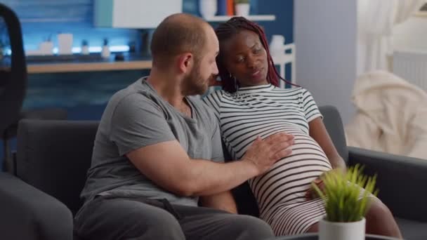 Interracial pareja esperando niño en sala de estar - Metraje, vídeo