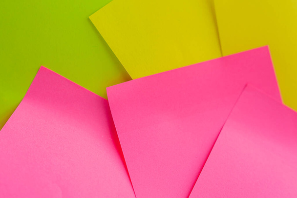 黄色、緑、ピンクの粘着性のあるノートが白い背景に閉じられます。カラーペーパーノート。最小限の概念に戻る - 写真・画像