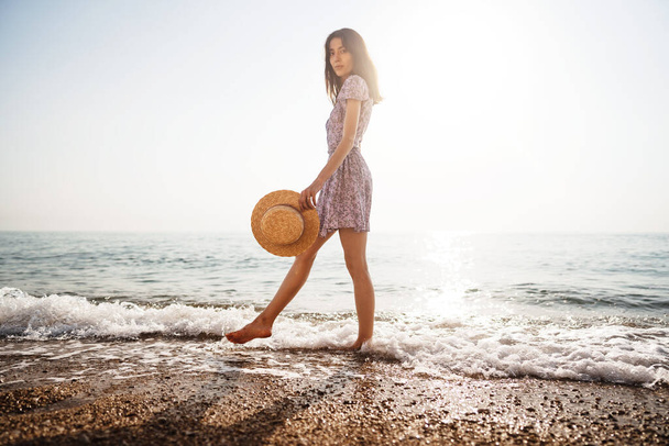 Giovane donna solitaria cammina sulla riva del mare al tramonto - Foto, immagini