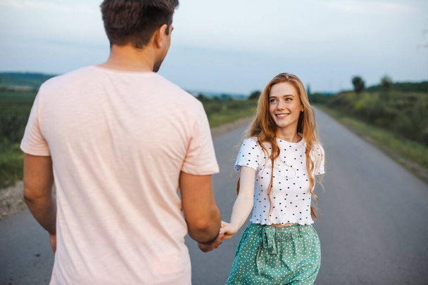 Couple holding hand and walking on road. Beautiful ginger woman with freckles. Love concept - Φωτογραφία, εικόνα