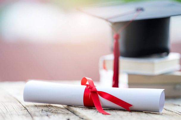 Enfoque selectivo de cerca de un tope de graduación o un certificado de título de mortero y diploma puesto sobre la mesa - Foto, imagen