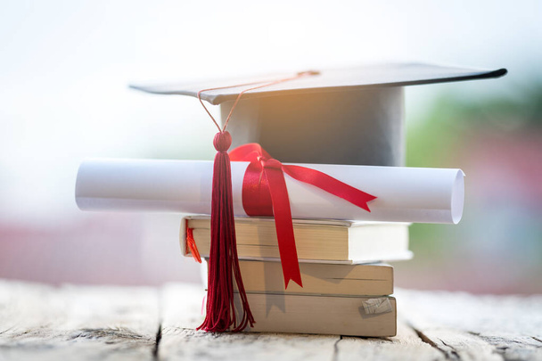 Крупный план выборочного фокуса выпускной шапки или строительной доски и диплома диплома, поставленных на стол - Фото, изображение