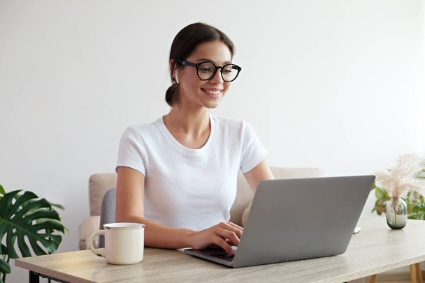 Online education concept. Young beautiful brunette woman wearing eyeglasses taking part in a group video call. Portrait of female college student studying at home. Close up, copy space, background. - Valokuva, kuva
