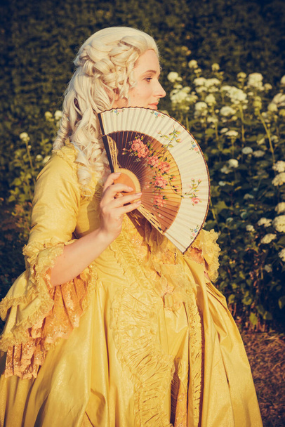 Portrait of blonde woman dressed in historical Baroque clothes with old fashion hairstyle, outdoors. Luxurious medieval dress - Fotografie, Obrázek