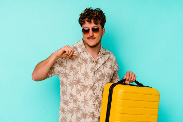 Nuori matkamies, jolla on keltainen matkalaukku sinisellä pohjalla, tuntuu ylpeältä ja itsevarmalta, esimerkiltä seurata. - Valokuva, kuva