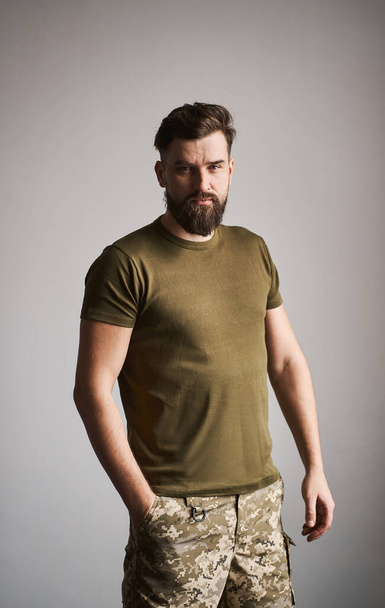 Good-looking military bearded guy on gray background - 写真・画像