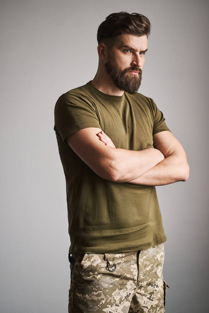 Portrait of a handsome military man holding arms crossed on gray background - Foto, Imagen