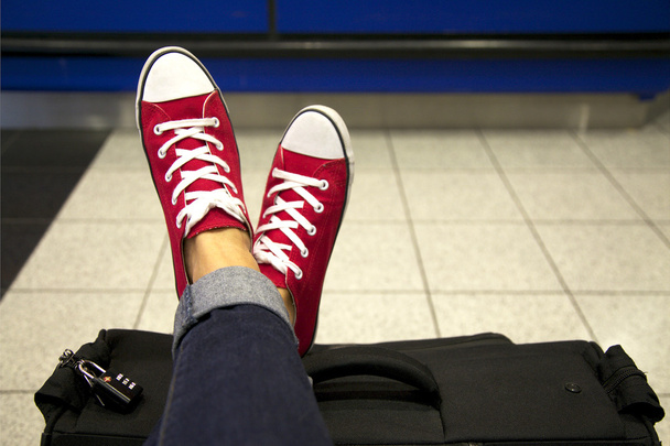 Frauenfüße in roten Turnschuhen auf dem Koffer - Foto, Bild