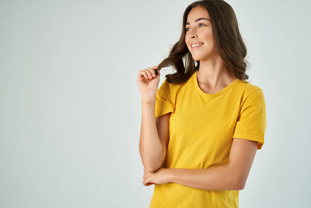 alegre morena en amarillo camiseta posando sonrisa recortada vista aislado fondo - Foto, Imagen