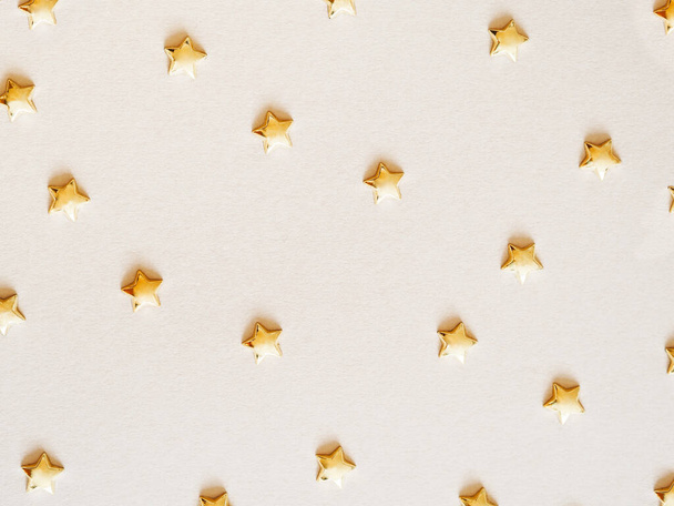 Partie motif de décoration brillant étoiles dorées sous la forme de confettis sur fond beige plat laïc. Vue du dessus - Photo, image