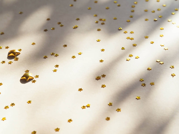 Patrón de decoración brillante fiesta - estrellas doradas en forma de confeti con sombra sobre fondo beige plano laico. Vista superior - Foto, Imagen