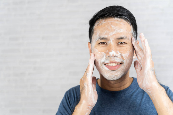 Férfi használ hab mosás az arcát szürke háttér - Fotó, kép