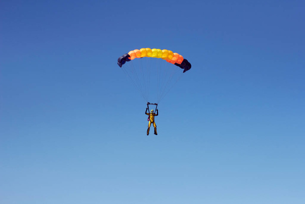 Flug eines erfahrenen Fallschirmjägers mit einem professionellen Fallschirm am Himmel, Orientierung und Landung auf Präzision - Foto, Bild