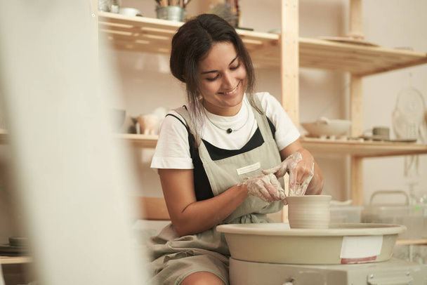 Happy woman working in pottery studio - Foto, imagen