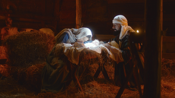 Maryja i Józef pieszczą Dzieciątko Jezus w oświetlonym żłobie - Zdjęcie, obraz