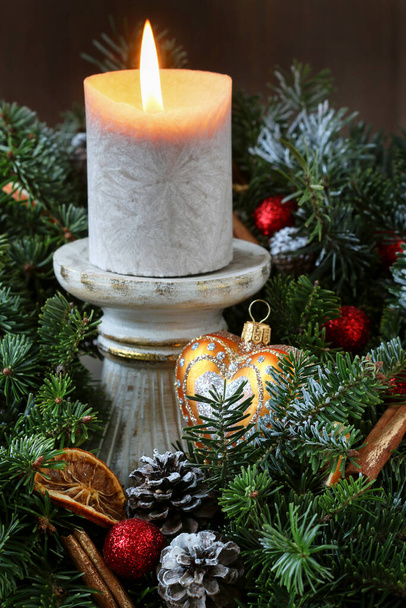 Christmas decoration with fir twigs, red apples, oranges, cones and cinnamon sticks. Classic winter arrangement. - Φωτογραφία, εικόνα