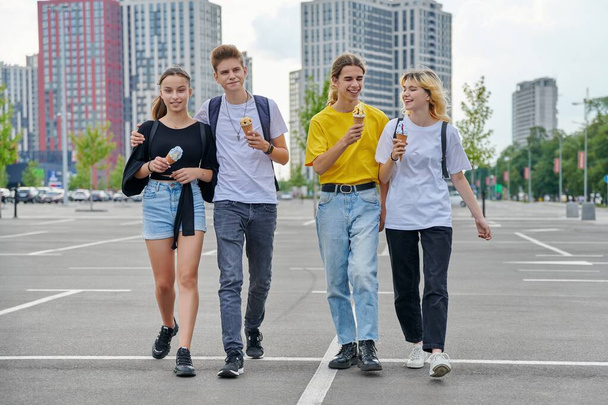 Group portrait of happy teenagers walking together with ice cream - 写真・画像