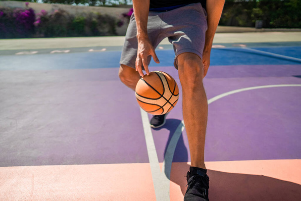 Jambes d'un joueur de basket professionnel dribble la balle sur le terrain de basket - Photo, image