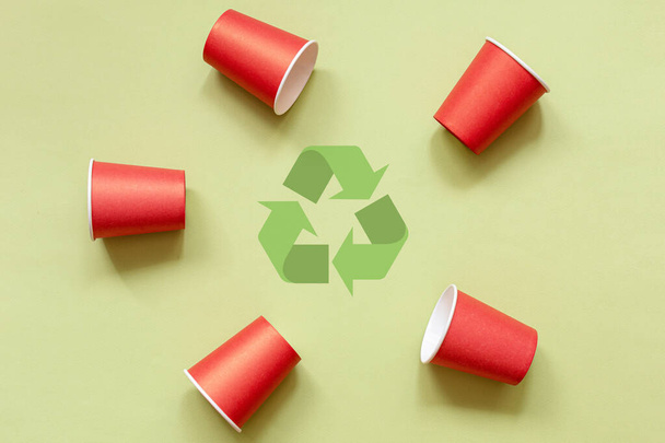Paper cups and recycling symbol on green background. Set red paper cups. Top view. Concept - environmentally friendly, zero waste, plastic free. Copy space. Flat lay - Foto, Bild