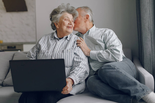 Elegant old couple sitting at home and using a laptop - Φωτογραφία, εικόνα