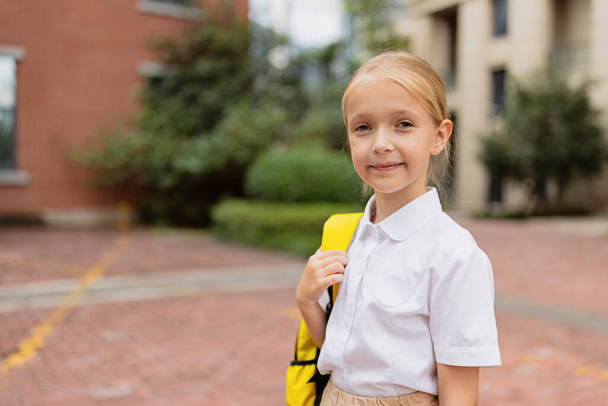 Schoolgirl back to school after summer vacations. Child in uniform standing early morning outdoor.  - Fotoğraf, Görsel
